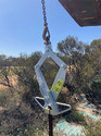 Silver T-Post-Pulla Extraction Tool hanging from a loader bucket.